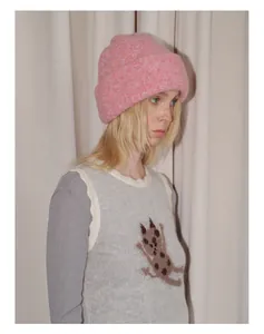 Detail of pink wool blend knit beanie showing thick seamless texture on model