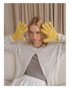 Nahaufnahme gelber Grobstrickhandschuhe kombiniert mit einem weißen Strick-Cardigan-Outfit