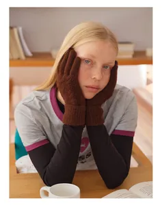 Détail de gants en laine mélangée marron foncé à torsades portés dans un décor hivernal doux