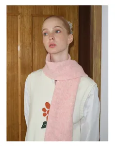 Nahaufnahme eines weichen rosa Strickschals mit Rippenmuster und floraler Strickweste