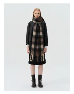 Detail view of thick brown and black plaid wool scarf with twisted fringe tassels