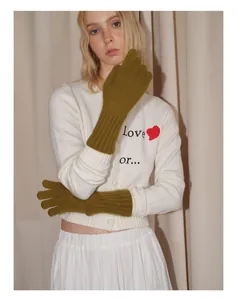 Detail of olive green long knit touchscreen gloves worn with a white embroidered cardigan