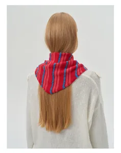 Detail of red and blue striped knitted wool blend neckerchief on white sweater