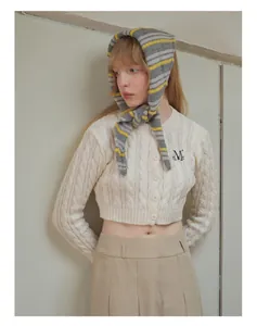 Detailed knit texture of wool blend striped scarf with classic cable knit cardigan