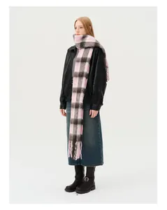 Detail of pink and brown plaid wool blend scarf with long tassels on a model