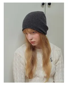 Dettaglio della trama del berretto in lana australiana grigio scuro e cardigan in maglia