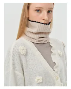 Detail of wool knit neck warmer with 3D floral accents and contrast scalloped edges