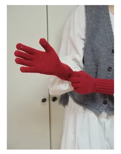 Dettaglio di guanti in lana rosso scuro con aperture sulle dita per schermi touchscreen