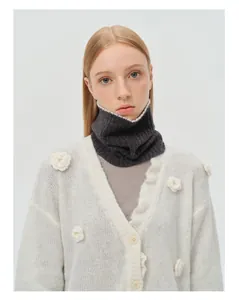 Close-up of white knitted cardigan with 3D floral details and dark grey neck warmer