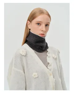 Detail of high-count wool neck warmer with pearl edge and white knit cardigan ruffles