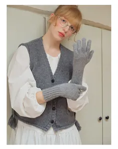 Dettaglio di lunghi guanti in maglia grigia con texture lana e gilet con frange eleganti