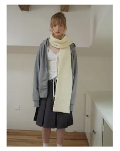 Detail of soft cream-white wool blend knitted scarf showing thick plush texture and minimalist edge