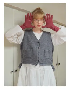 Dettaglio di guanti in lana paillettes rosso scuro abbinati a un gilet di maglia