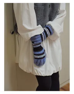 Detail von Strickhandschuhen mit bunten Streifen auf weicher hellblauer Wollmischung