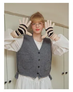 Nahaufnahme von gestreiften Plüsch-Strickhandschuhen und grauer Vintage-Weste mit Fransen