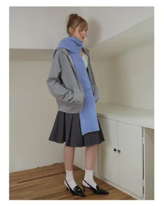 Detail of bright blue wool blend scarf paired with a grey zip hoodie and pleated skirt