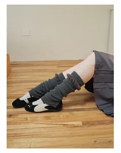 Dettaglio di scaldamuscoli in maglia grigio scuro con pizzo e sneakers ballerina