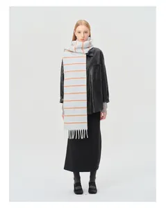 Détail de l'écharpe en laine à rayures avec franges blanches sur veste en cuir noir