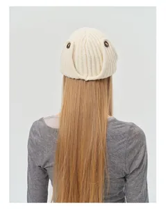 Detail of cream knitted wool aviator hat featuring decorative brown buttons and ribbed texture