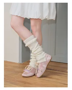 Dettaglio di scaldamuscoli in maglia bianca con frange e sneakers in raso rosa stile balletto