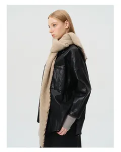 Detail van beige wollen sjaal met bruine handstiksels en een zwart leren jasje
