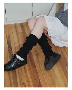 Dettaglio di scaldamuscoli in maglia a coste nera con frange su scarpe basse nere