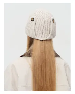 Close-up of beige rib-knit wool blend aviator hat featuring decorative brown buttons