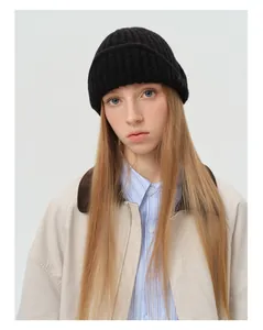 Close-up of black wool blend knit aviator beanie showing thick ribbed texture and rolled edge