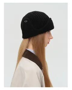 Detail of black wool blend knit aviator hat featuring ribbed texture and side button accent