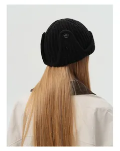 Detail view of black wool-blend knit aviator hat showing earflap texture and button