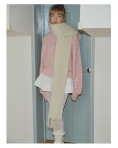 Detail van zachte crème wollen sjaal met extra lange franjes op roze vestje