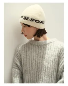 Detail einer gemütlichen cremeweißen Wollstrickmütze mit Buchstaben-Jacquard-Muster