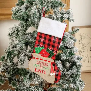 Classic red and black buffalo plaid Christmas stocking hanging on a snowy festive tree