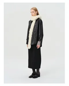 Full view of women's black leather coat styled with a white wool scarf and black skirt