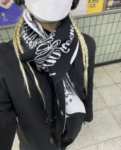 Detail shot of black and white knitted scarf with letter patterns on a wool coat