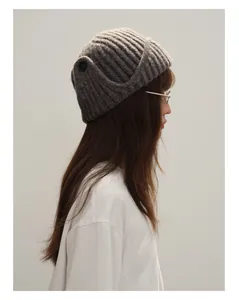 Close-up of dark grey wool blend knitted beanie with ribbed texture and black button detail