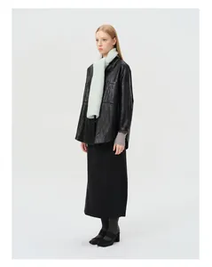 Detail view of a soft mint green wool blend knit scarf paired with a black leather jacket
