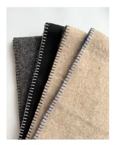Detail van wollen sjaals met contrasterende stiksels in grijs, zwart en beige kleuren