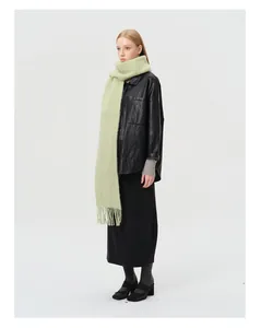 Detailopname van zachte pistachegroene wolmix sjaal met dikke kwastjes en pluche textuur