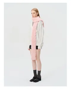 Detailed view of a long pink plush knit wool scarf worn over a white floral cardigan