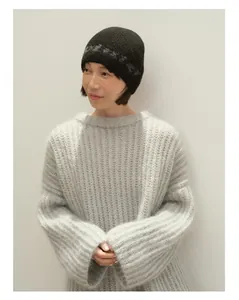 Detaillierte Strickstruktur aus hellgrauem Wollpullover und schwarzer Muster-Beanie