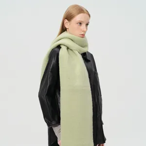 Dikke lichtgroene wolmix sjaal met franjes gedragen door een model in winterse modestijl