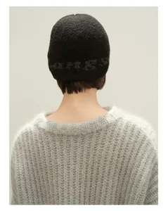 Nahaufnahme der Wollmütze mit Jacquard-Schriftzug und weichem Mohair-Strickpullover