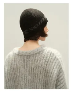 Nahaufnahme der dunkelgrauen Wollmütze mit eingewebten Buchstaben und weichem Strickpullover