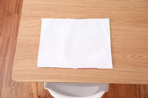 Close-up of a rectangular white fabric placemat with neat stitched edges on wood