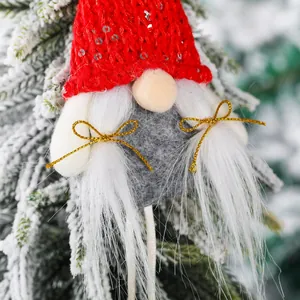 Charmanter roter Strick-Weihnachtszwerg mit Pailletten an einem verschneiten Baum