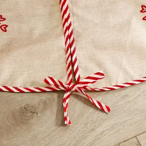 Close-up of faux linen Christmas tree skirt with red striped bow and heart print