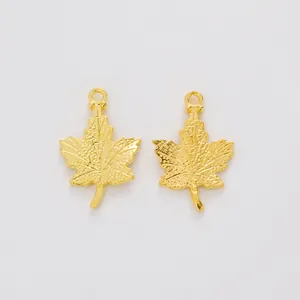 Detailed macro view of two golden maple leaf alloy pendants with intricate vein textures