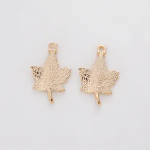 Macro detail of golden maple leaf charms showing intricate vein textures and metal finish