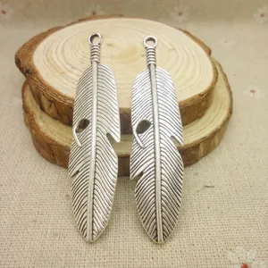 Détail des pendentifs en plumes en alliage argenté antique sur un fond en bois rustique